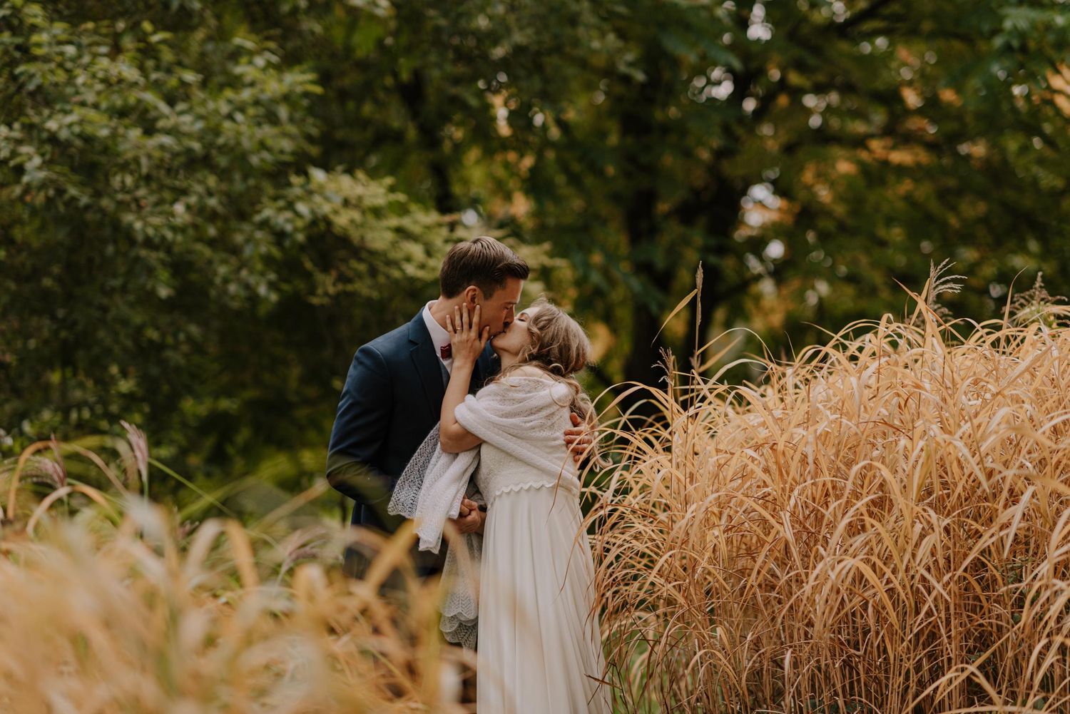 Couple embraces in golden wheat field during romantic autumn wedding photoshoot.