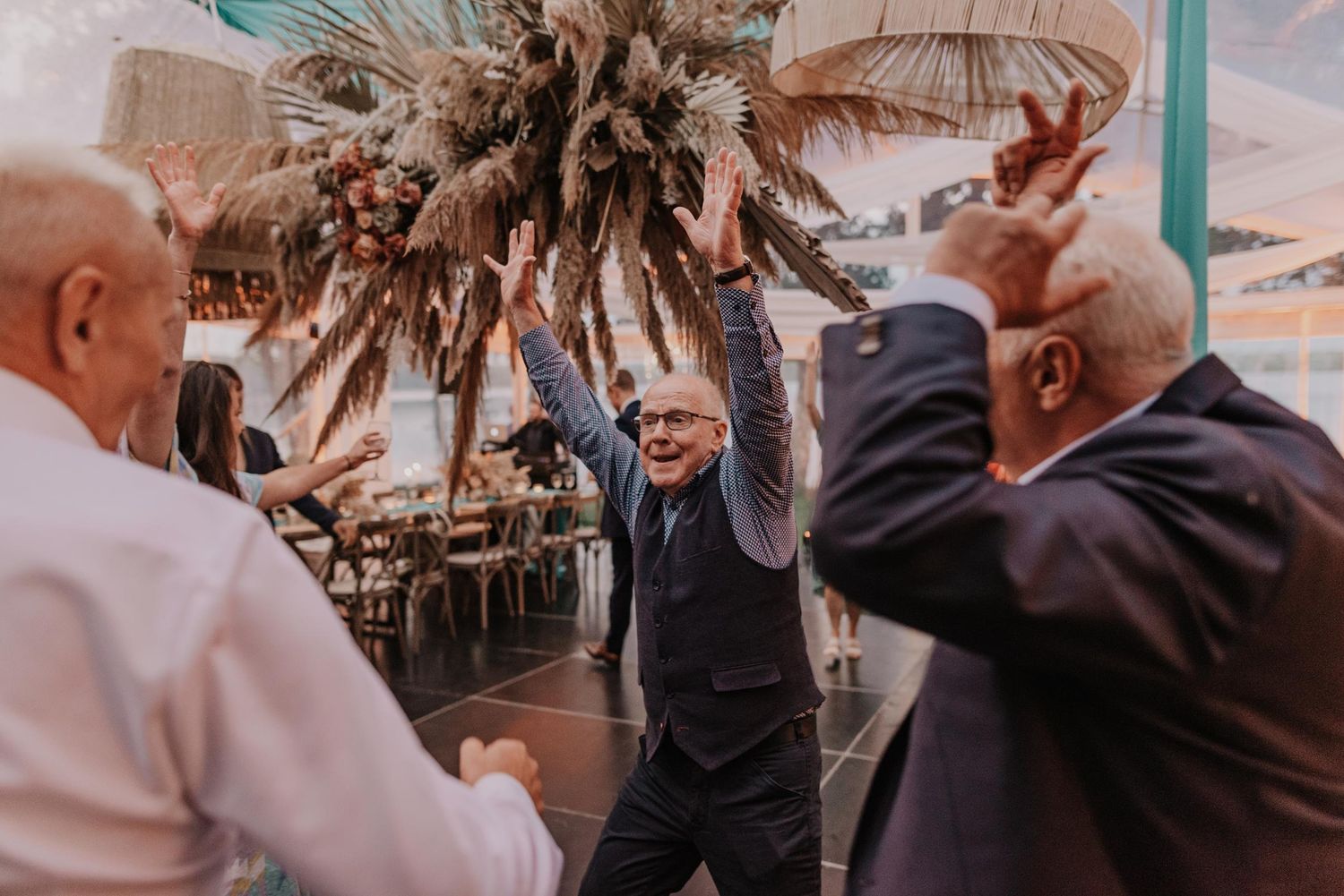 Wedding celebration with guests dancing under decorative lighting.