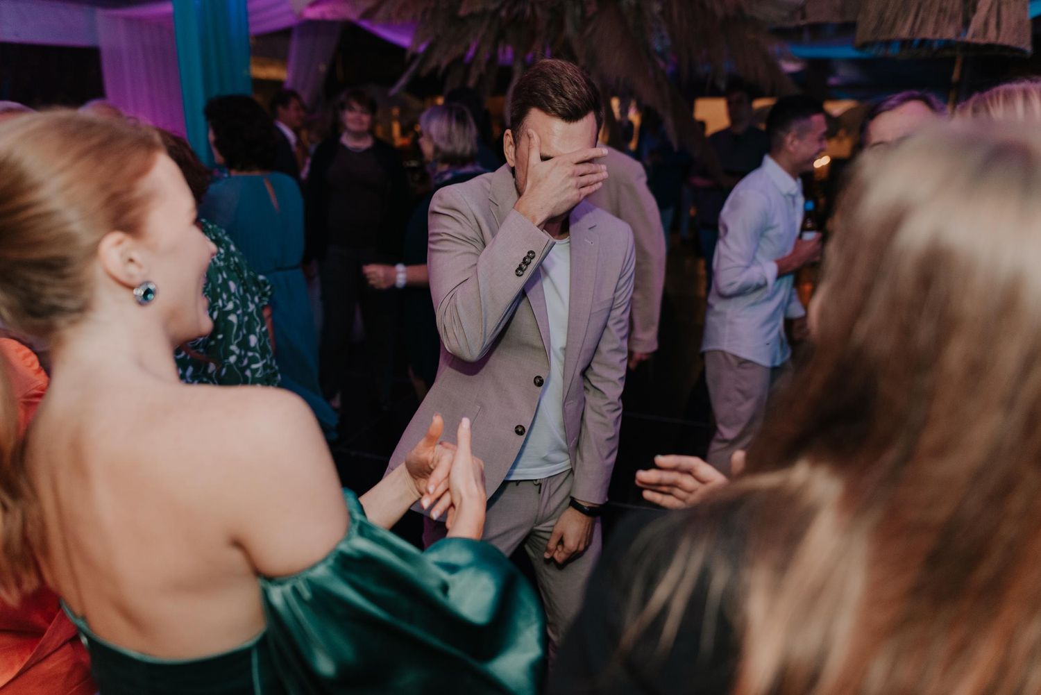 Wedding guests dancing and celebrating on a dimly lit dance floor.