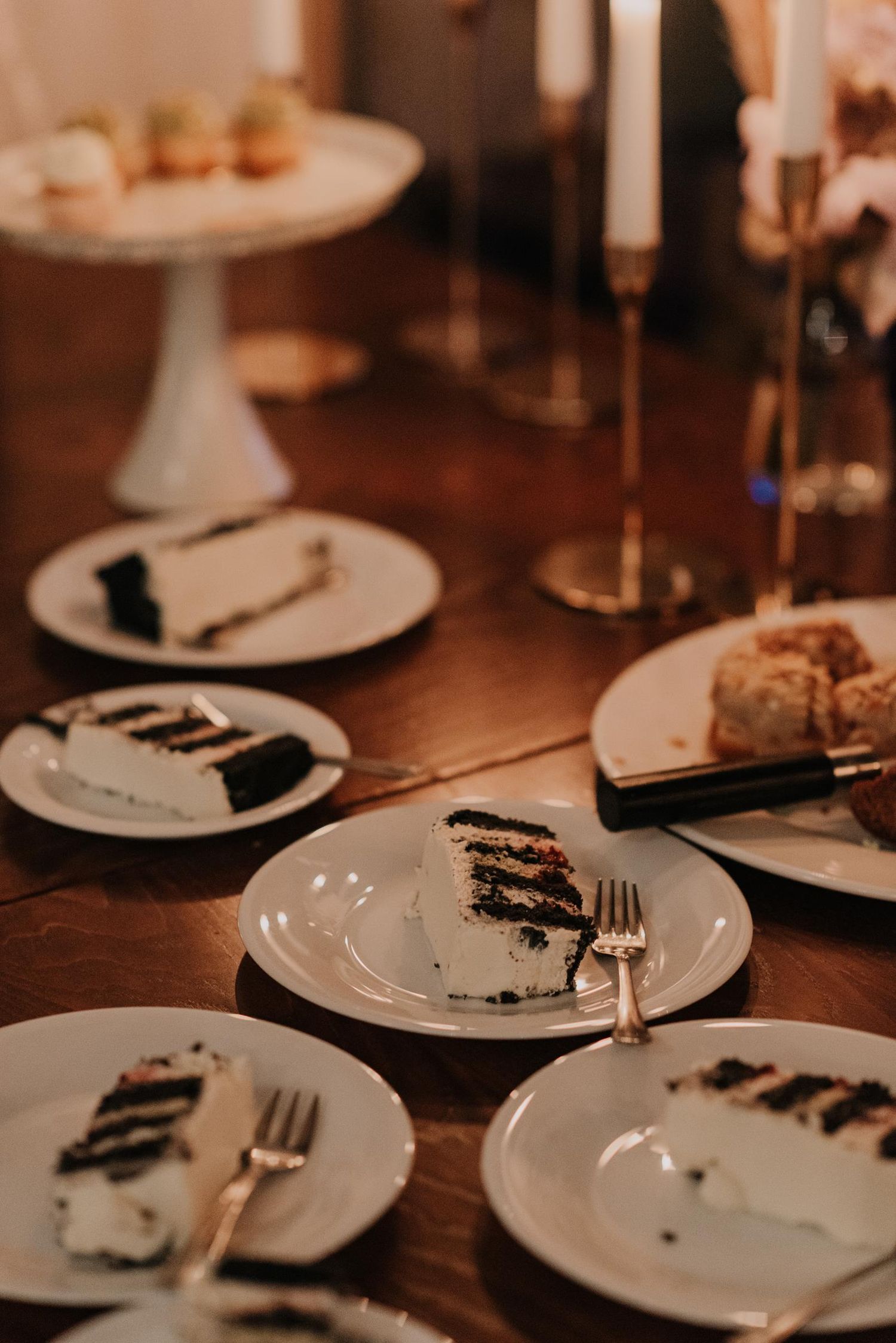 Half-eaten slices of wedding cake on white plates with forks.