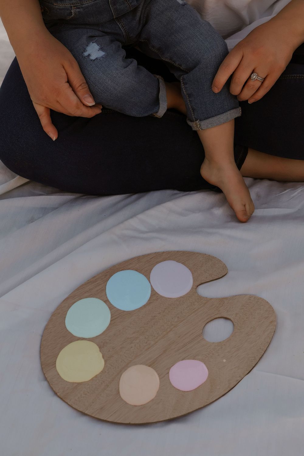 Creative flat lay showing hands arranging pastel colored circles on a beige art palette.