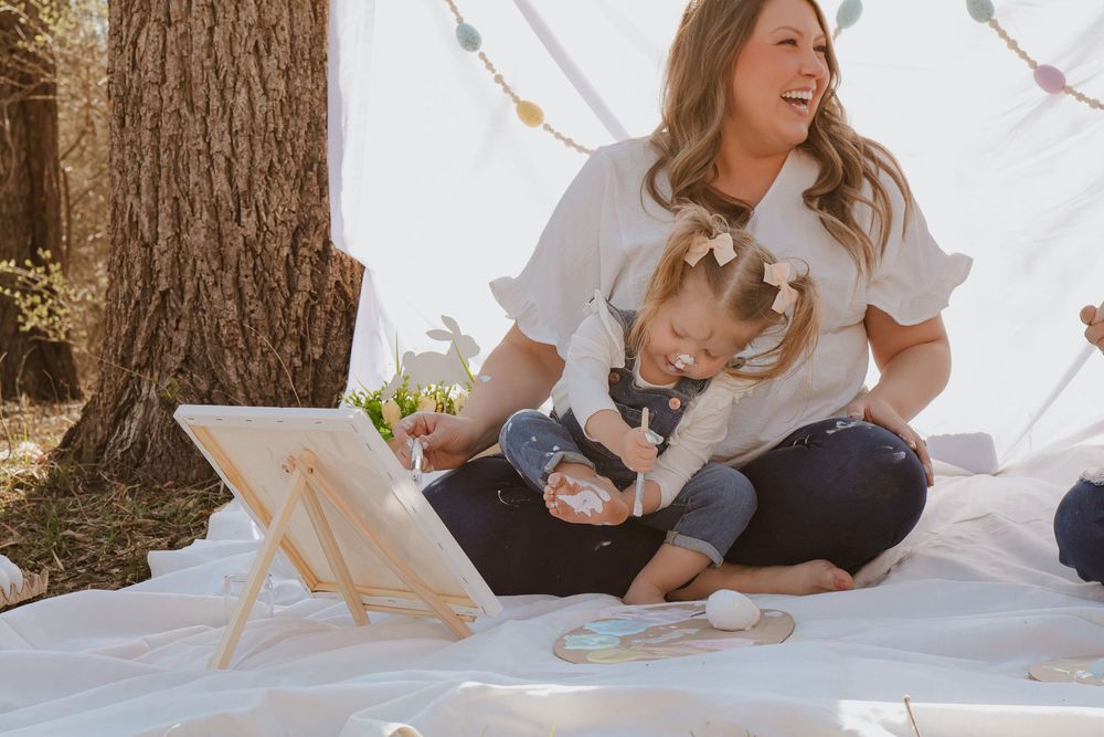 Candid moments captured on white blanket during outdoor family photoshoot.