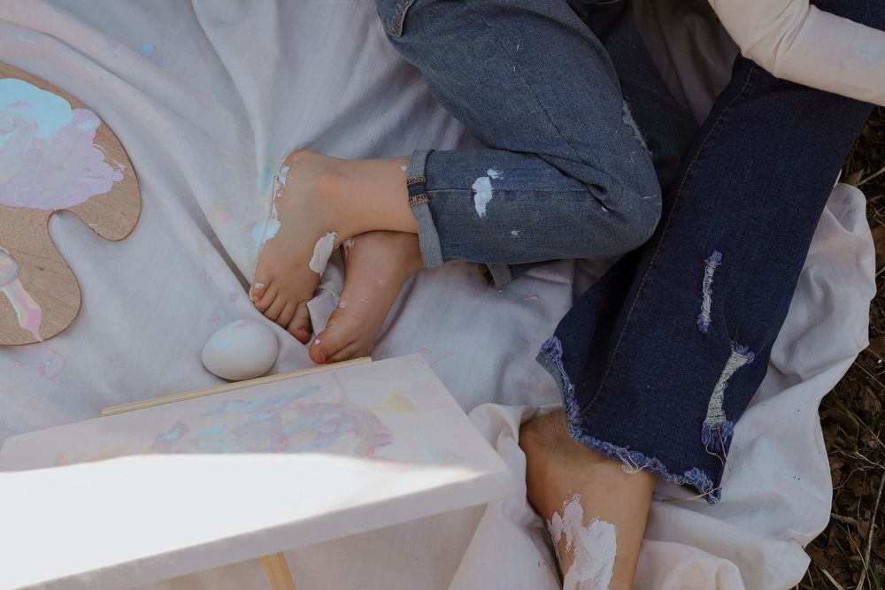 Playful interaction on white blanket during outdoor family photo session.