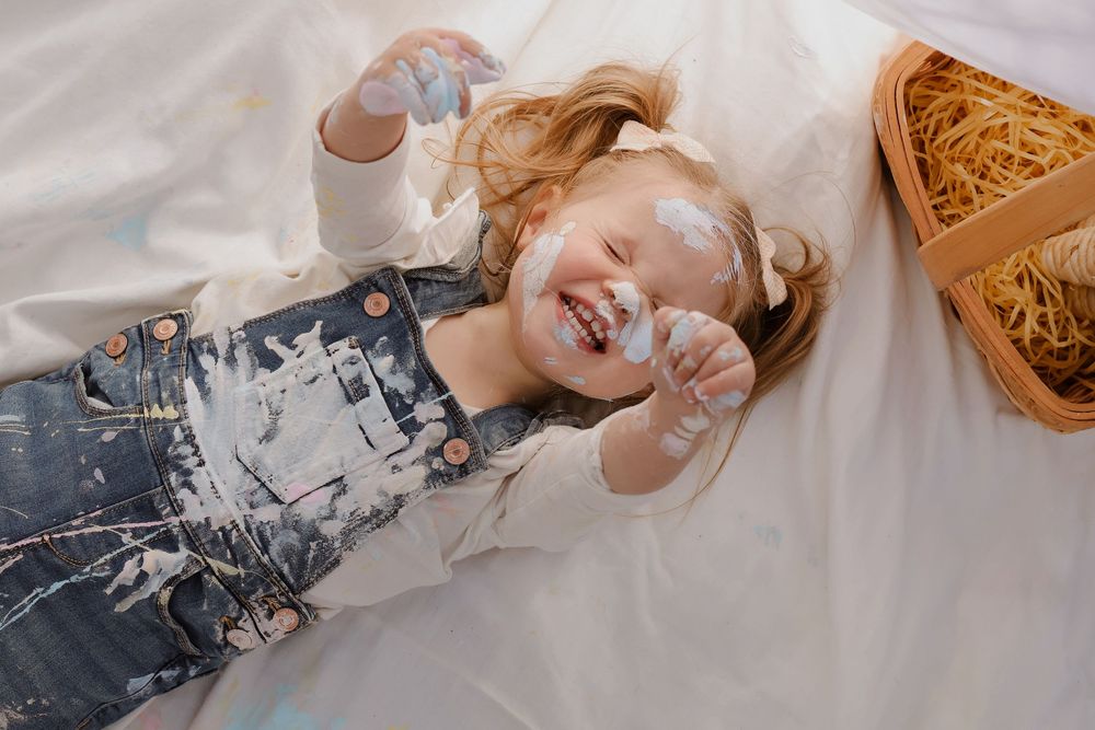 Playful poses on white blanket during outdoor family photoshoot.