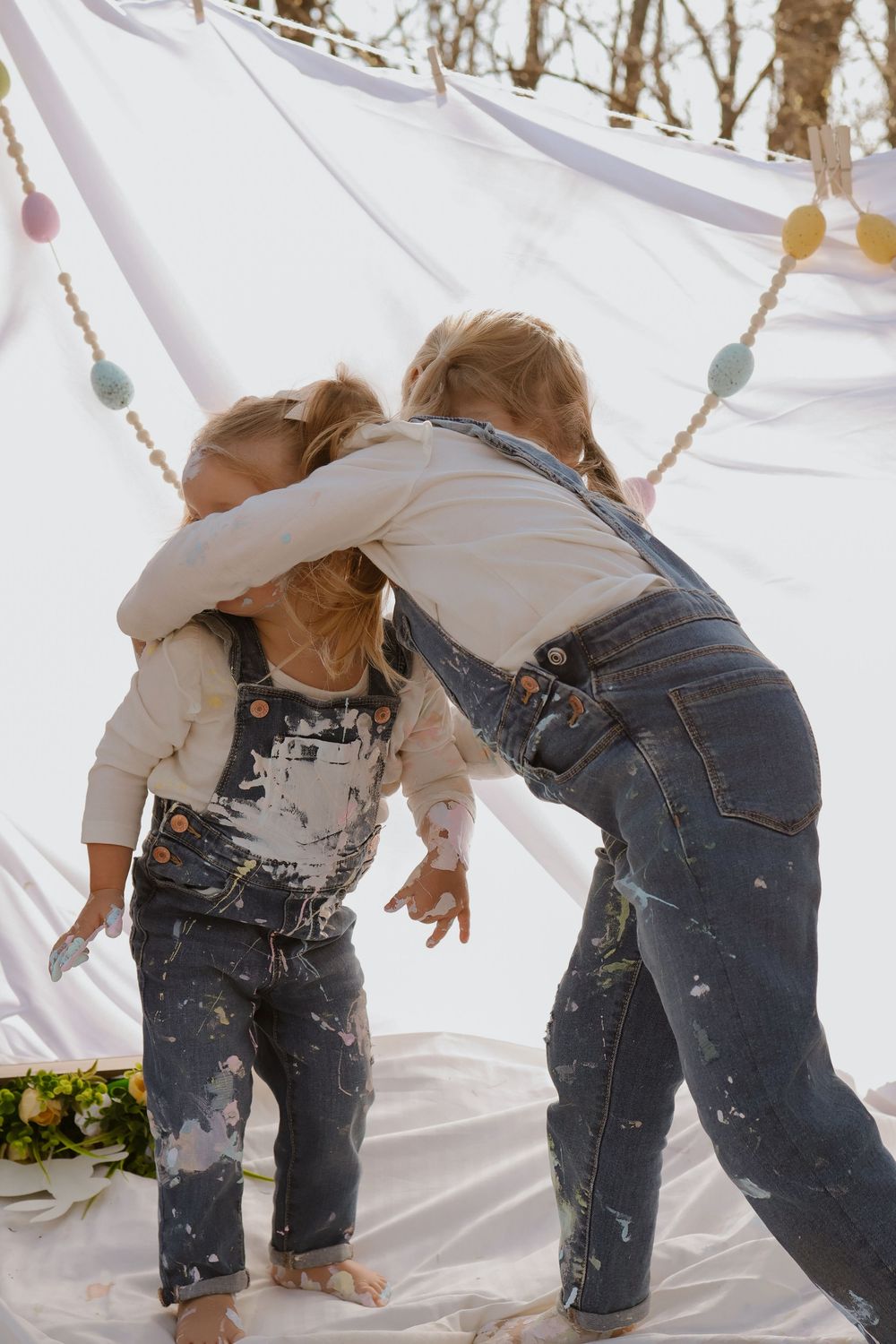 Creative play session with paint splatters and white fabric backdrop on a sunny day.