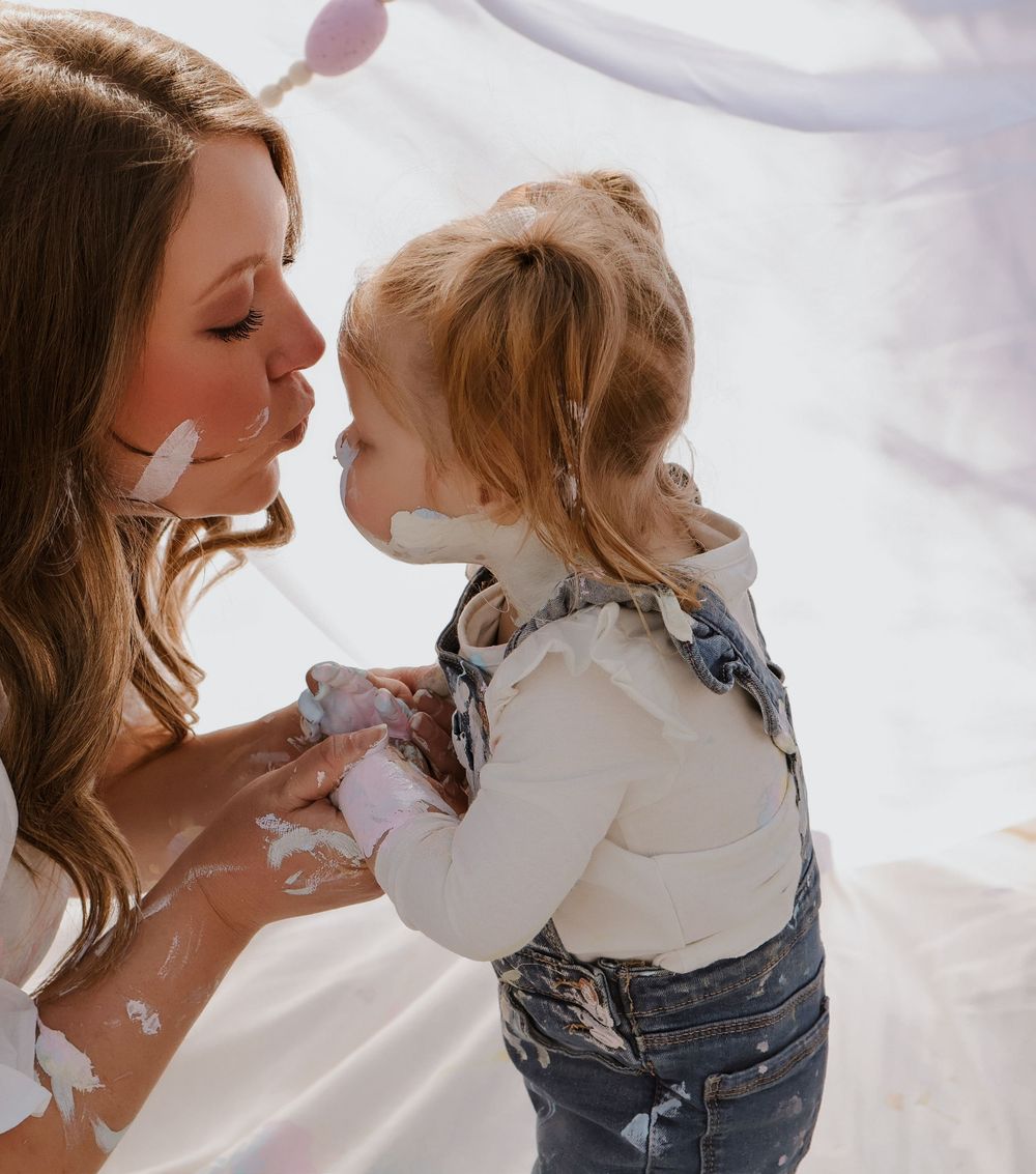 Sweet interactive moment during creative paint play with white fabric backdrop.