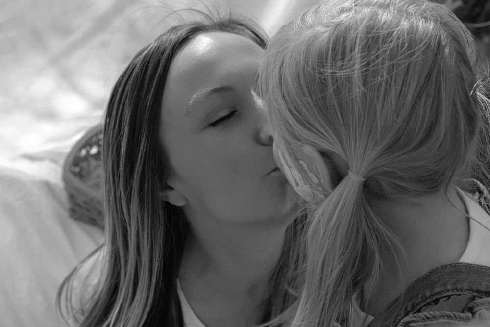 Tender moment captured during an artistic photoshoot with white backdrop.