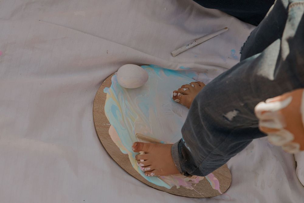 Paint-covered hands creating art on white surface during creative play.