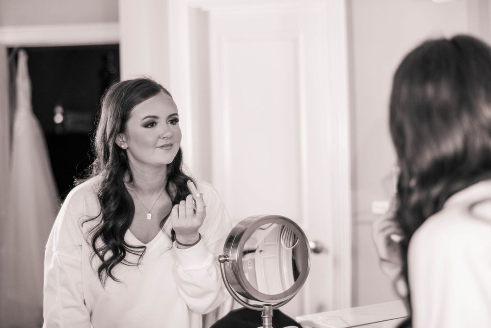 A reflection of someone applying makeup in a vanity mirror.