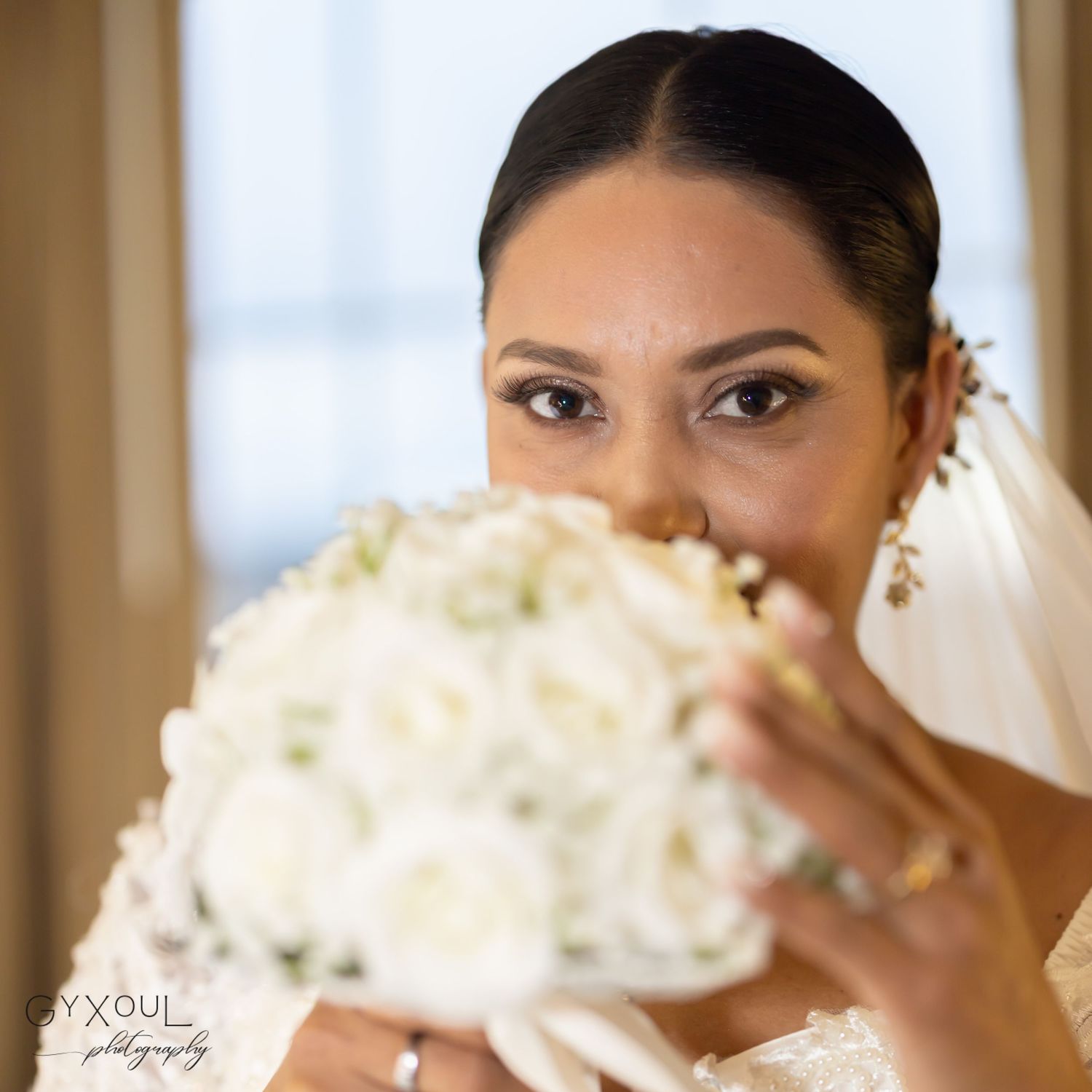 Bridal portrait with a white rose bouquet peeking over the face.