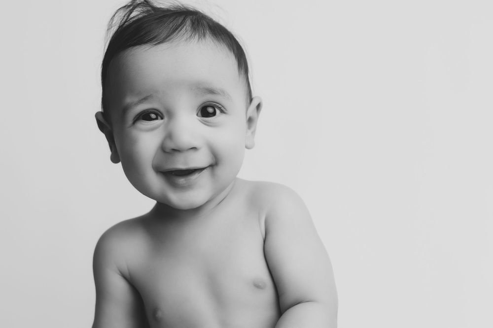 Black and white portrait of a happy smiling baby with bright eyes against a light background.