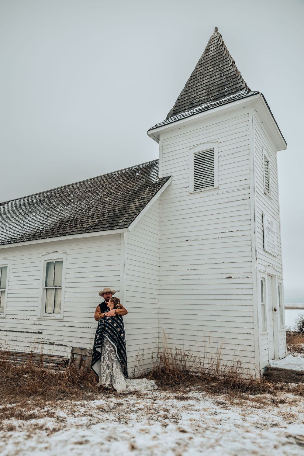 Winter wedding photography session at classic white country church in snowy setting.