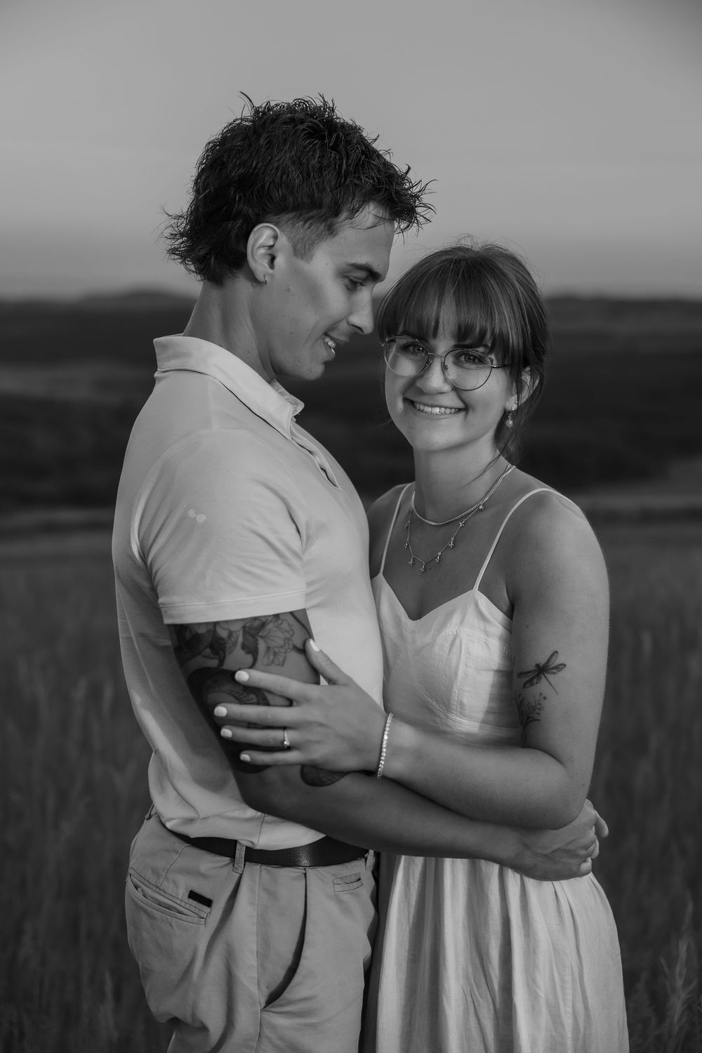 Intimate black and white portrait of couple embracing in outdoor setting.