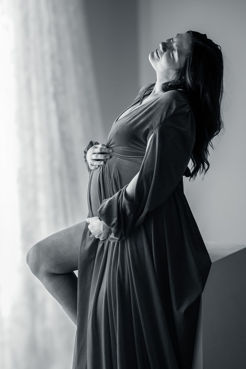 Moody black and white maternity portraits showing silhouetted figure in flowing dress.