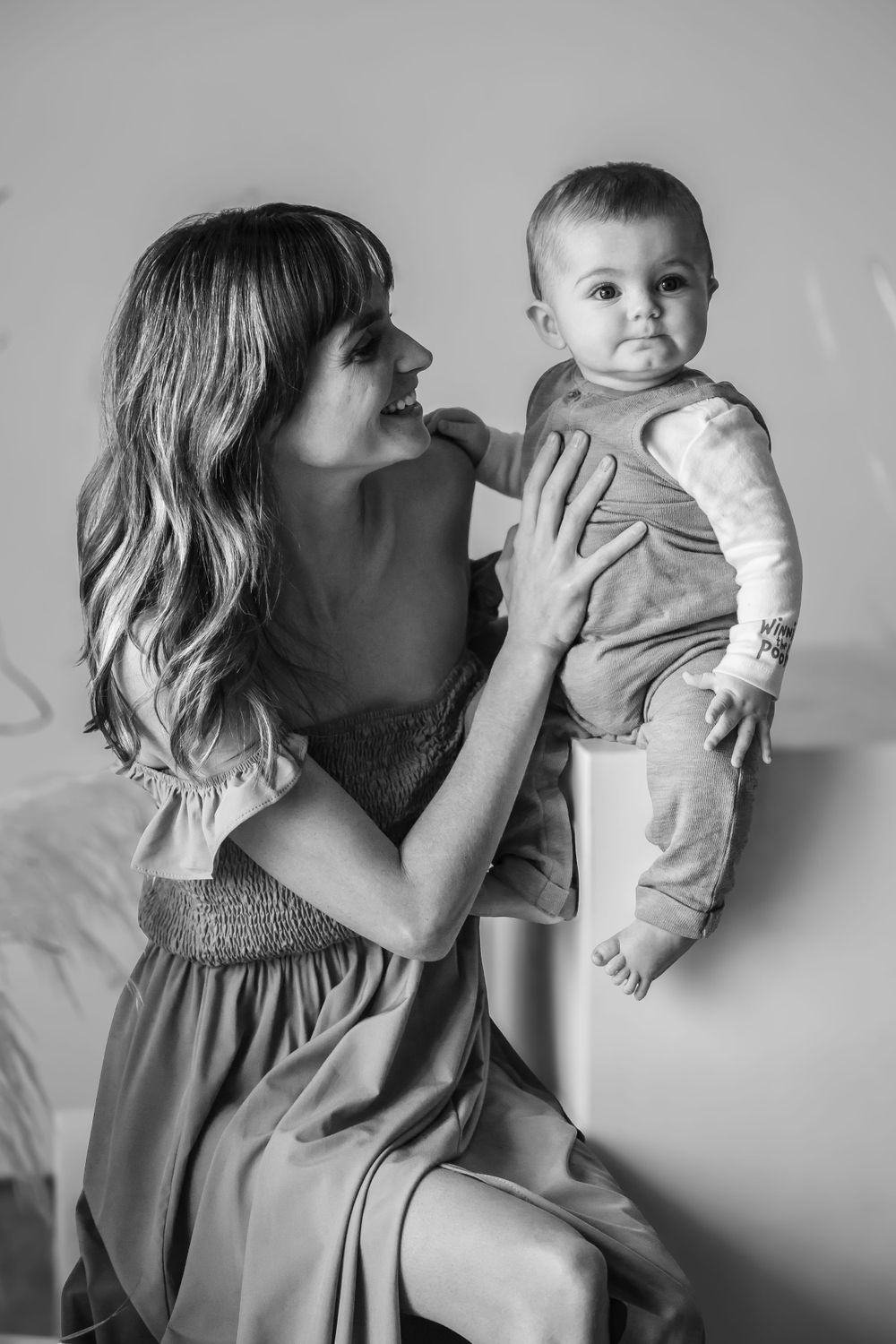 Black and white photos show tender moments between parent and infant in intimate portrait series.