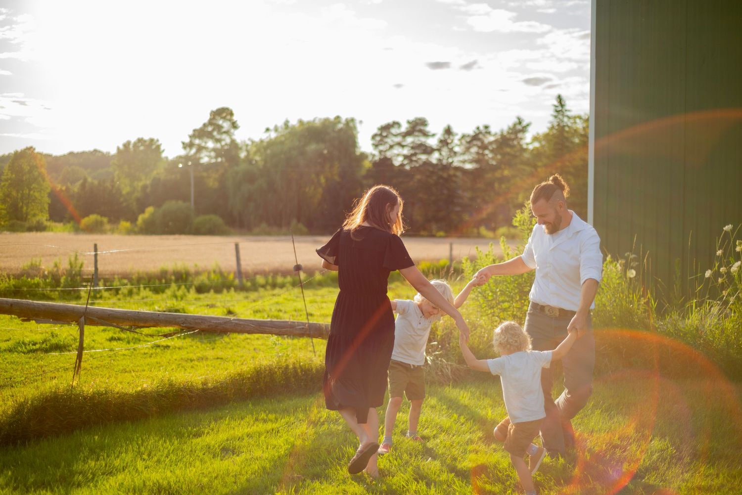 Multiple hands of different sizes and ages stack together in an intimate family moment captured in warm sunlight.