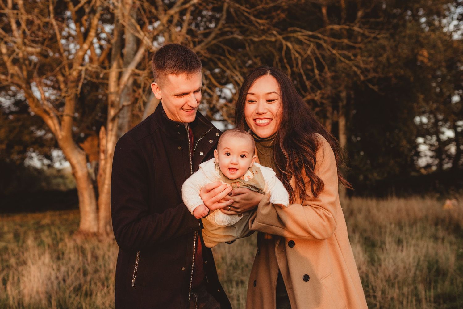 Mother and father playing with their baby in the soft evening light during a relaxed family photoshoot
