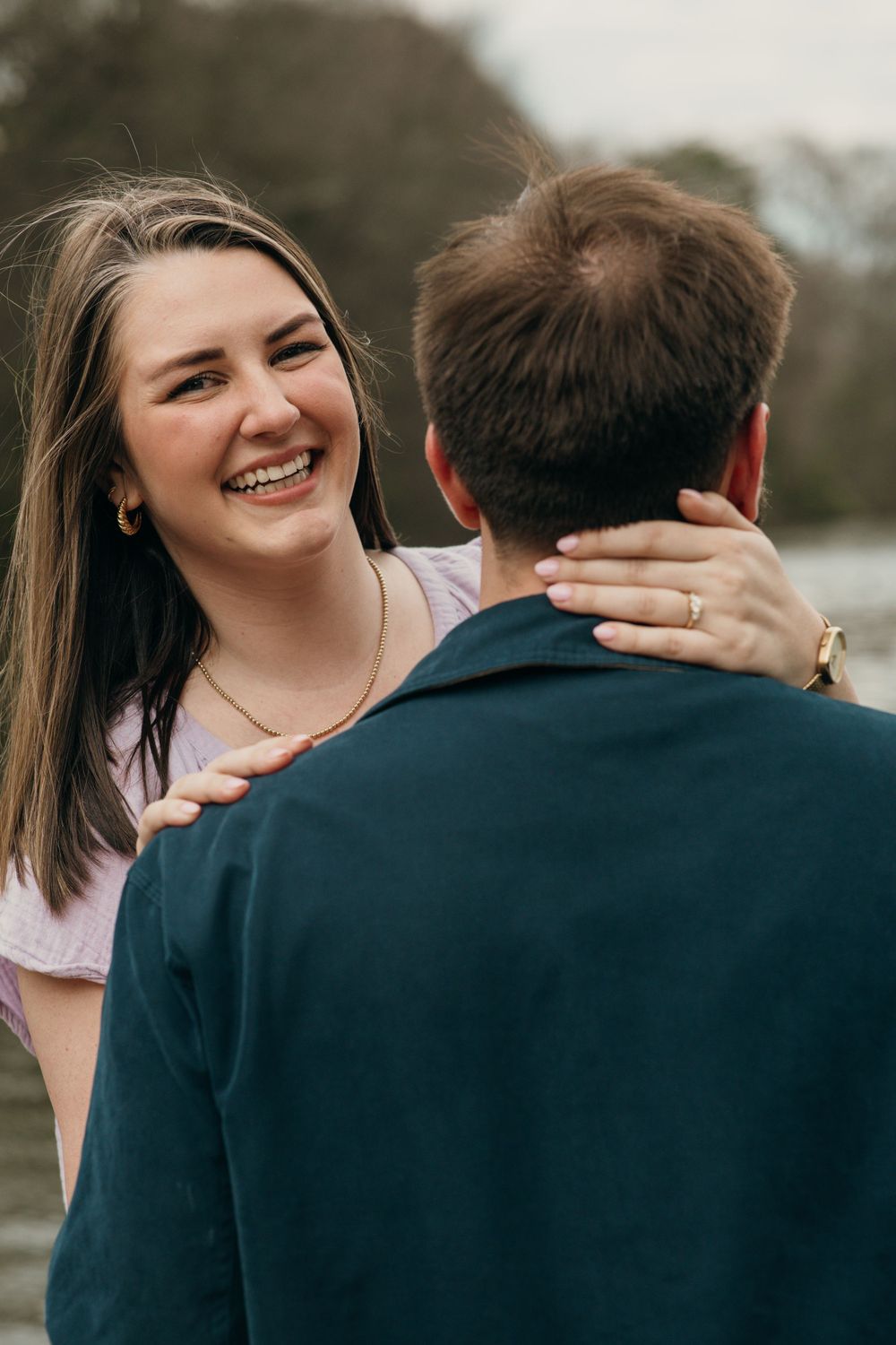 Joyful engagement photo of couple embracing on wooden dock by lake at Piedmont Park in Atlanta, Ga.