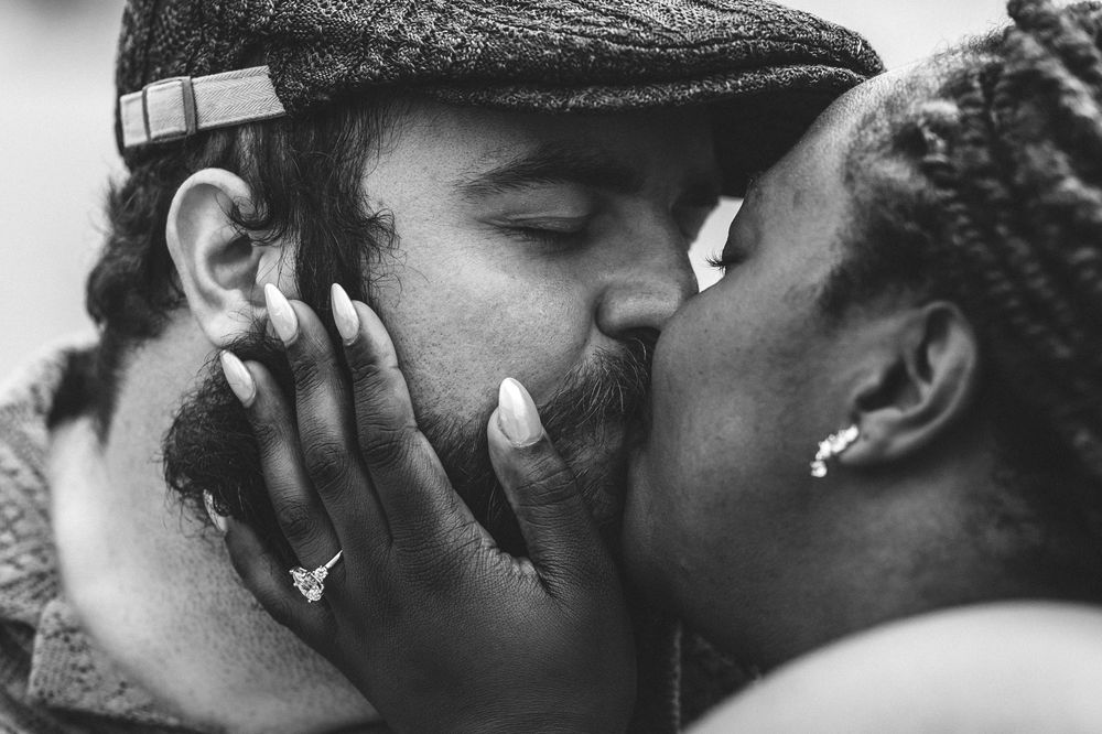 Intimate black and white photo shows people kissing and embracing in a tender emotional moment.