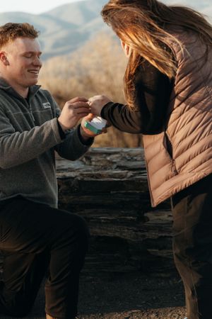 A proposal moment captured on a mountain overlook during golden hour.