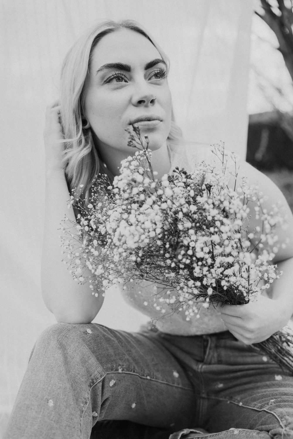 Black and white portrait photograph showing someone with blonde hair holding a bouquet of baby's breath flowers.