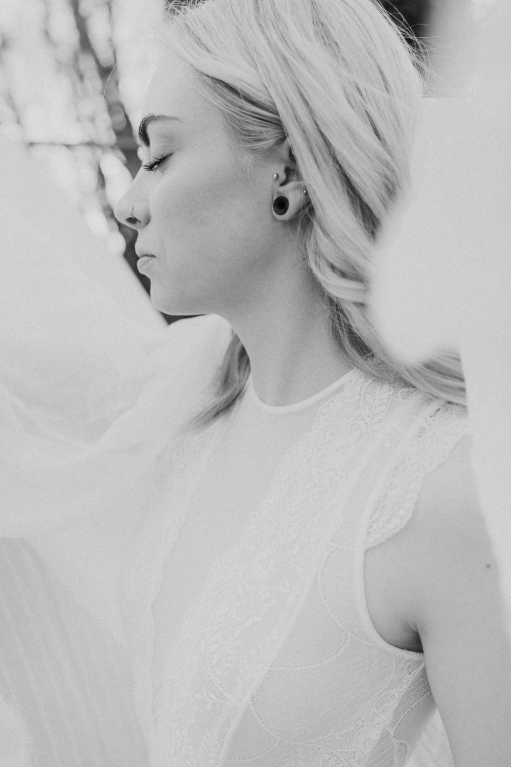 Ethereal black and white portrait of blonde woman in lace dress with eyes closed.