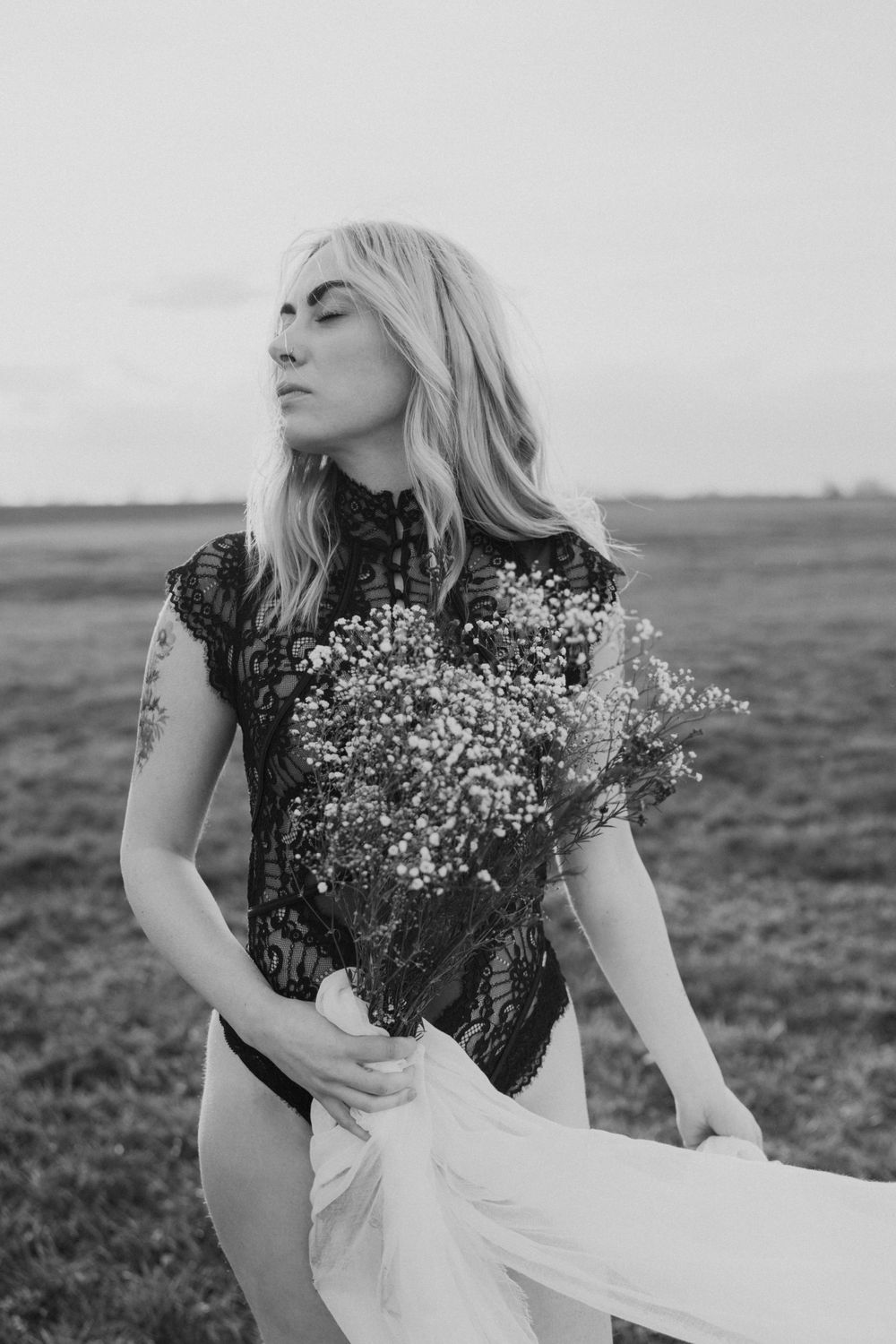 Black and white portrait with lace dress and baby's breath bouquet in field.