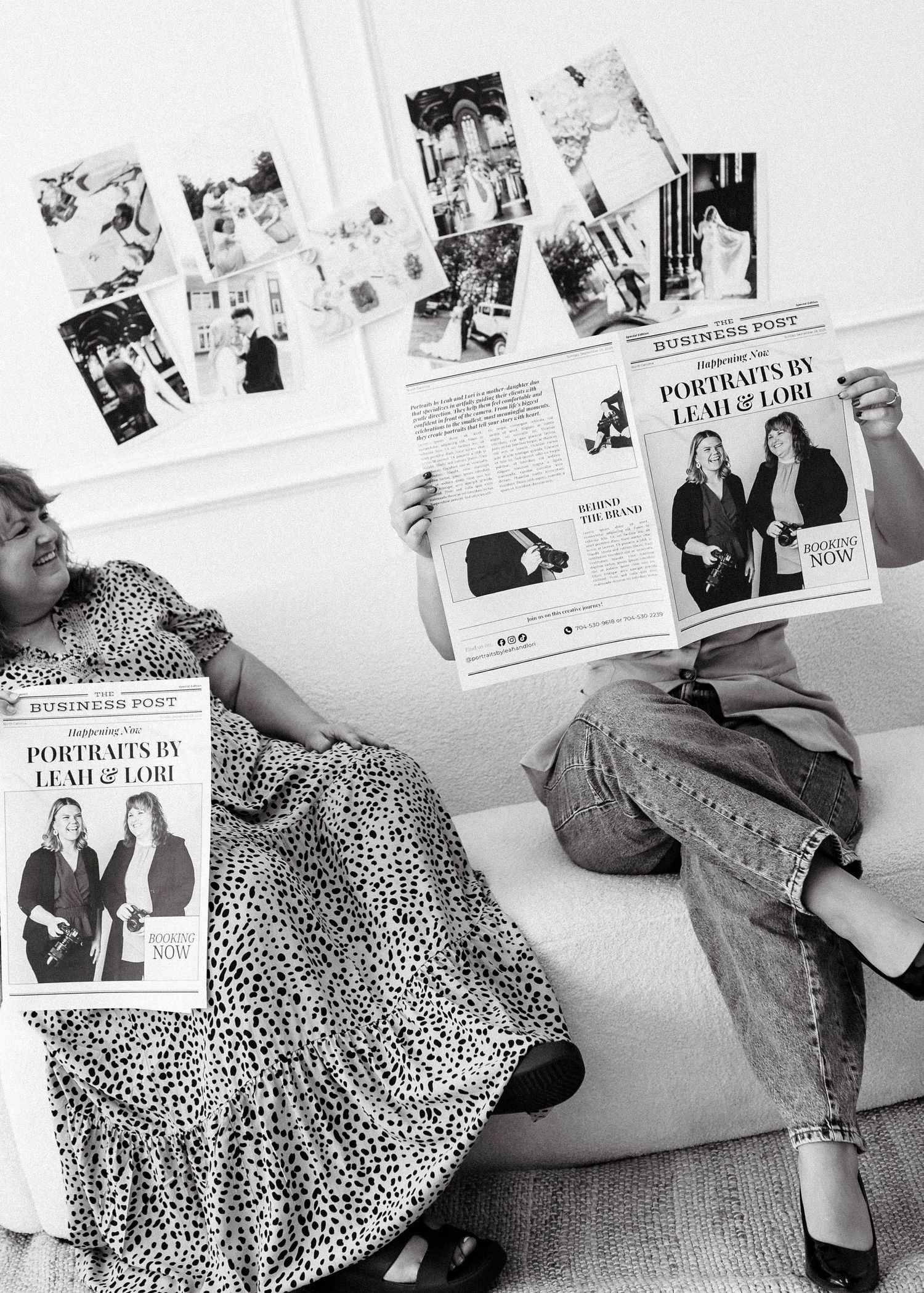 Black and white photos displayed on a white wall with photographers reviewing their work.