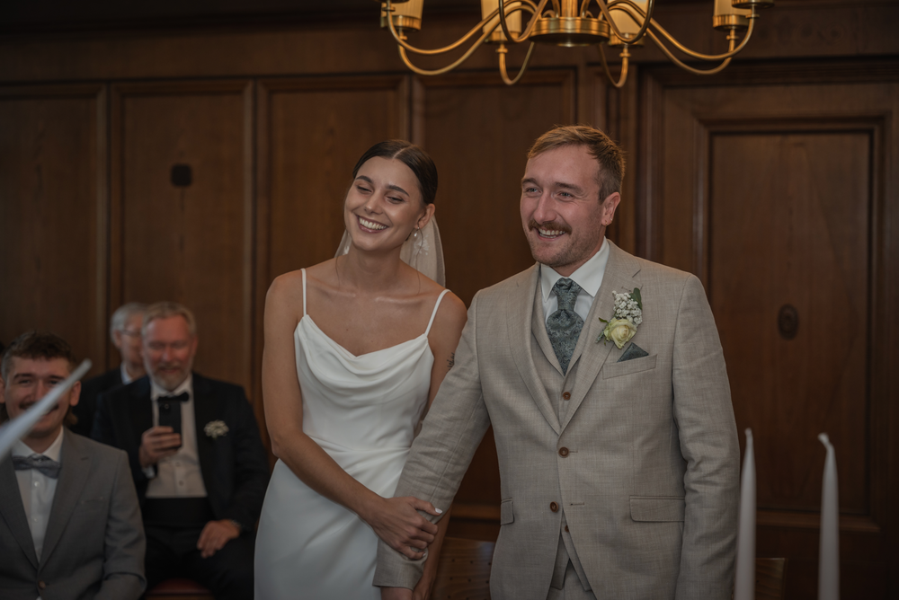 Ein fröhliches frisch vermähltes Paar in Hochzeitskleidung lacht gemeinsam während ihrer Feier in einer eleganten Location.