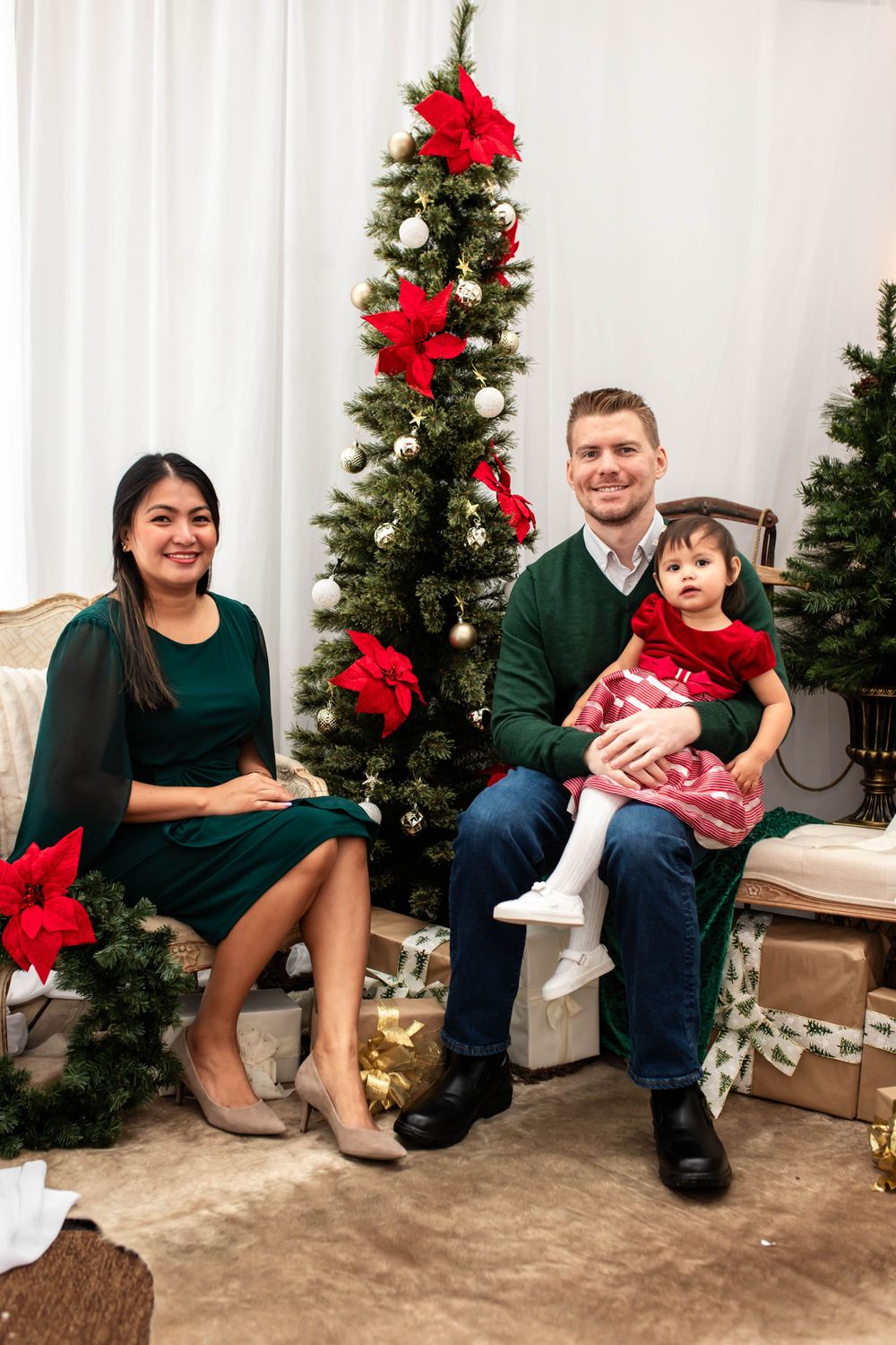 Festive holiday photo with decorated Christmas trees and red poinsettias in background.