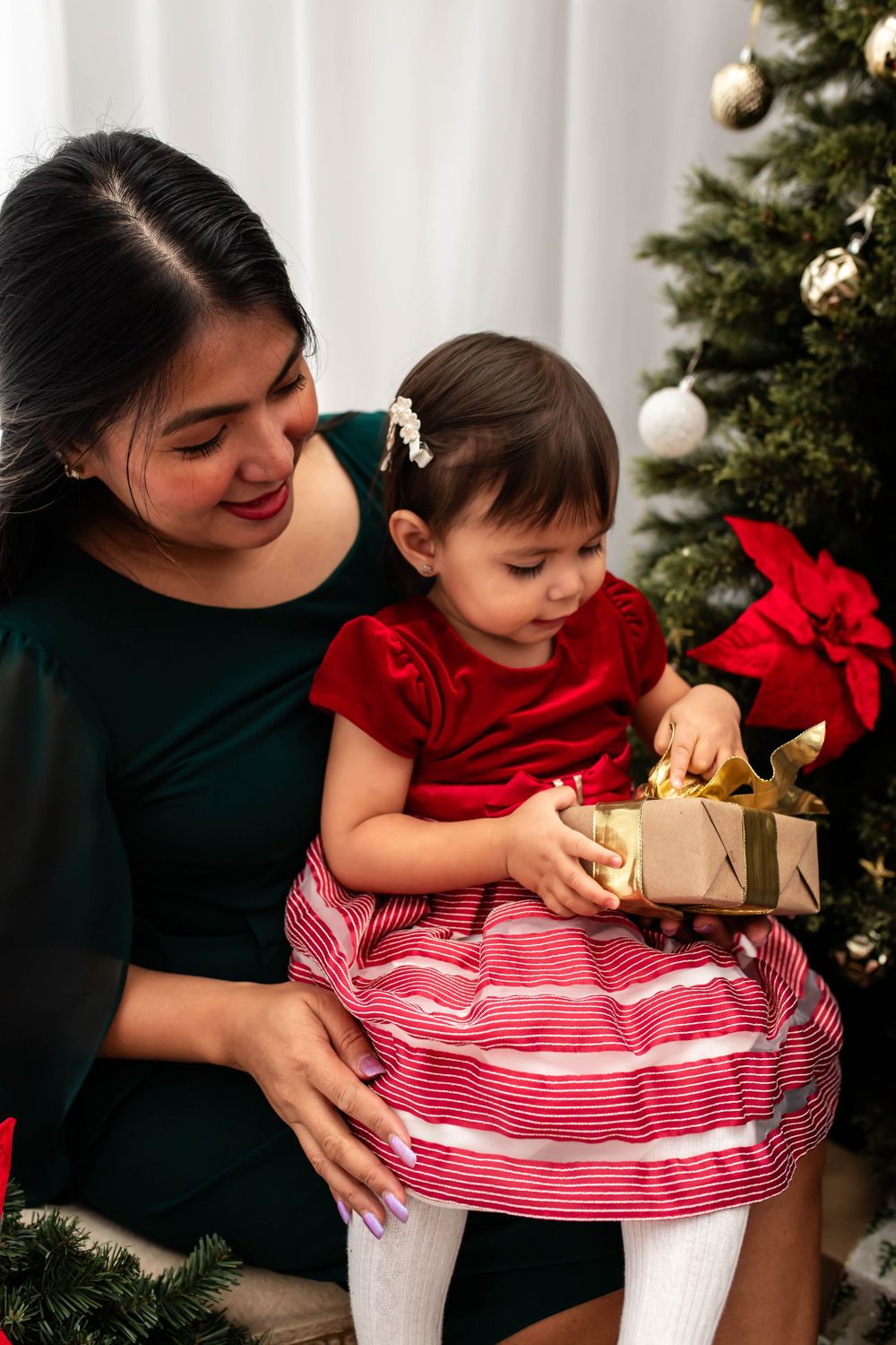 A festive Christmas scene with decorated tree as someone opens presents.