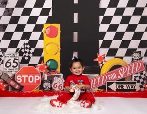 Baby during 2 Fast Cars-inspired milestone session in Glenview IL studio featuring race cars, checkered flags, and road-themed decor.