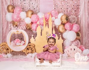 Baby during Princess Castle once upon a time-themed cake smash in Glenview IL studio with pink and gold decor, balloons, and castle props