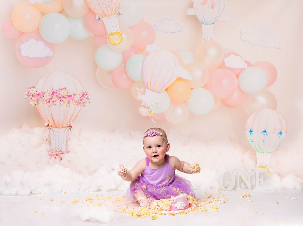 Baby during hot air balloon-themed cake smash in Glenview IL studio with pastel balloons, dreamy decor, and matching cake for first birthday