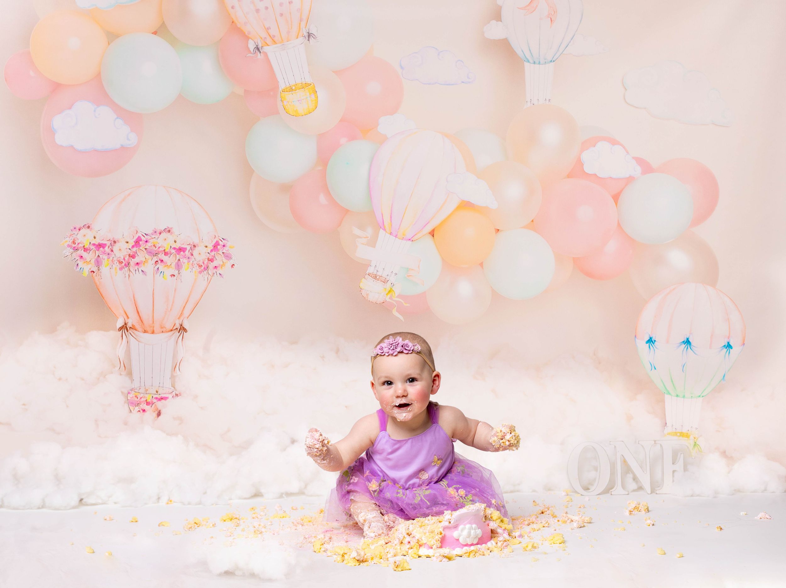Baby during hot air balloon-themed cake smash in Glenview IL studio with pastel balloons, dreamy decor, and matching cake for first birthday