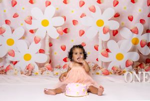 Baby during berries and daisies-themed cake smash in Glenview IL studio featuring daisy backdrop, strawberries, and whimsical decor.