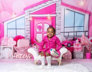 Baby during Barbie-themed cake smash in Glenview IL studio featuring pink decor, toy car, and dollhouse setup for first birthday.
