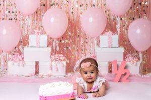 Baby celebrating half a birthday-themed cake smash in Glenview IL studio with pink decor, balloons, and playful setup.