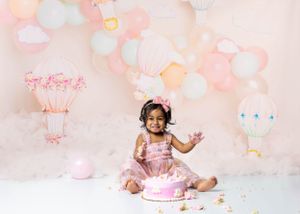 Baby during hot air balloon-themed cake smash in Glenview IL studio with pastel balloons, dreamy decor, and matching cake for first birthday