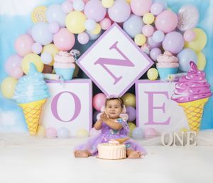 Baby during Sweet One-themed cake smash in Glenview IL studio featuring pastel balloons, ice cream props, and cake for first birthday
