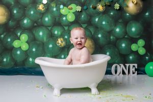 Baby during St. Patrick’s Day-themed cake smash in Glenview IL studio with green balloons, shamrocks, and festive decor for first birthday.