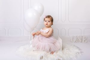Baby during simple cake smash in Glenview IL studio featuring a clean white backdrop, minimal decor, and a matching cake.