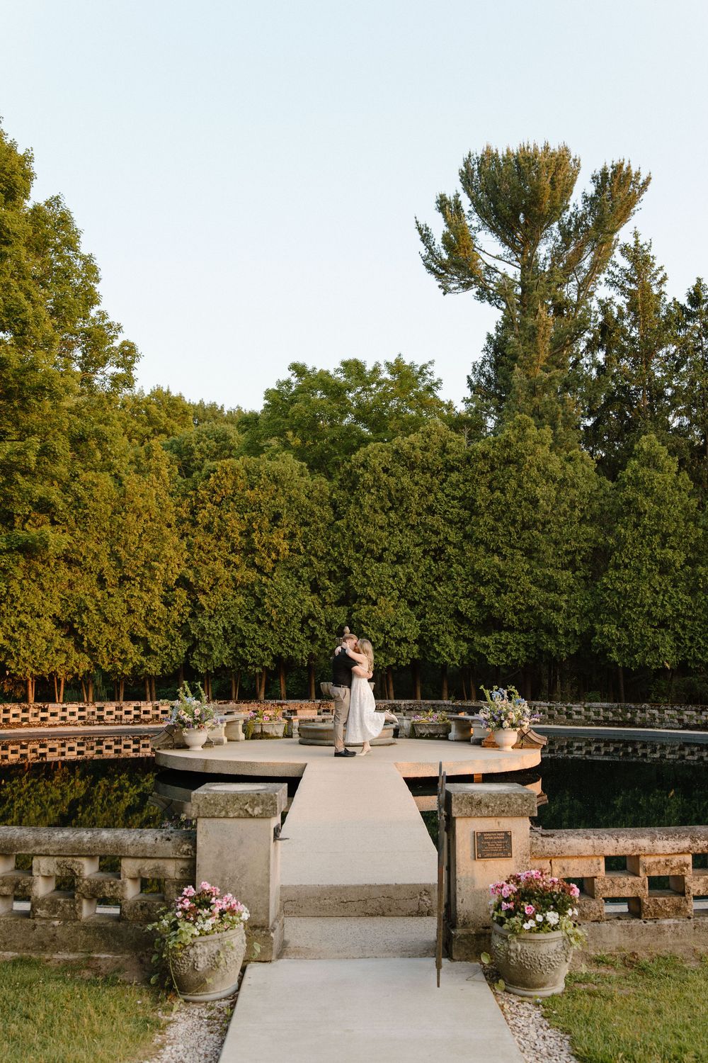 A romantic garden terrace with stone pillars and flower pots at sunset.