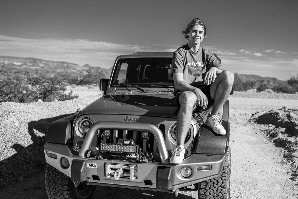 A vintage black and white photo collage showing a person sitting in a classic car on a desert road.