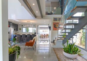 Modern entrance with double-height ceiling, glass staircase, and lush interior garden
