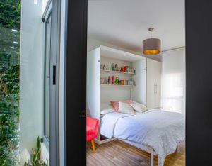 Bedroom with large glass windows, offering natural light and garden views