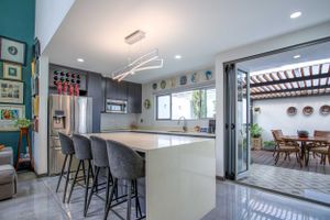 Modern kitchen with sleek countertops, bar seating, and open access to dining area