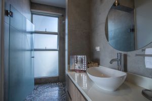 Luxury bathroom with contemporary design, glass shower, and round mirror.