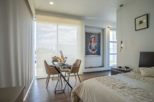 Master bedroom with workspace, modern furniture, and large windows.