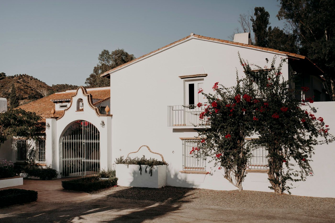 White Spanish colonial style building with arched entrance and bougainvillea flowers climbing the walls.